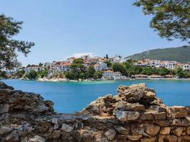 vista através de ruínas de pedras para a parte antiga da cidade de skiathos na ilha de skiathos, grécia. foto