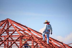 trabalhadores de solda instalando estrutura de armação de aço do telhado da casa no canteiro de obras foto