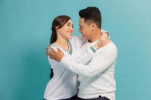 retrato de lindo casal jovem abraçando, olhando para a câmera e sorrindo, isolado em azul foto