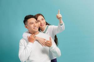 lindo casal feliz adora sorrir abraçando o dedo apontador para esvaziar o espaço da cópia, homem e mulher sorriem olhando para cima, foto