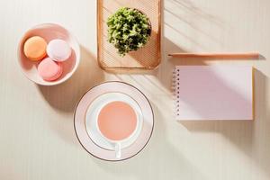 mesa de escritório bege com estilo fotografia stock com caderno em branco, biscoito, suprimentos e xícara de café foto