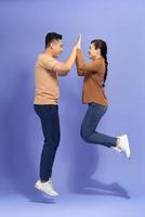 foto de casal alegre pulando dá highfive comemora vitória em fundo roxo