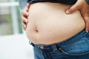 mulher asiática mostra excesso de peso e obesidade de tamanho grande barriga gorda no escritório. foto