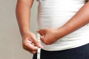 medir a gordura ao redor do homem gordo da barriga. foto