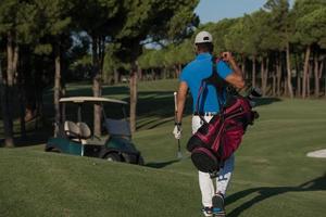 golfista andando e carregando bolsa de golfe foto