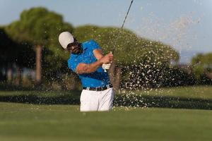 golfista profissional acertando um tiro de bunker de areia foto