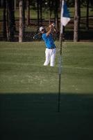 golfista profissional acertando um tiro de bunker de areia foto