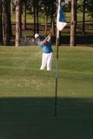 golfista profissional acertando um tiro de bunker de areia foto