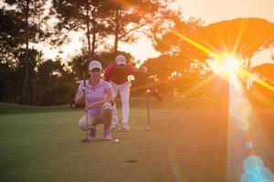 casal no campo de golfe ao pôr do sol foto