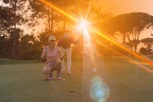 casal no campo de golfe ao pôr do sol foto