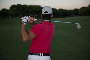 golfista acertando um bunker de areia no pôr do sol foto