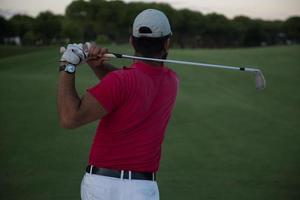 golfista acertando um bunker de areia no pôr do sol foto