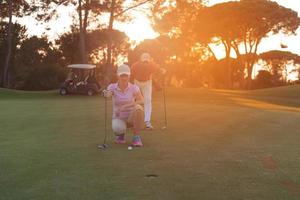 casal no campo de golfe ao pôr do sol foto
