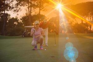 casal no campo de golfe ao pôr do sol foto