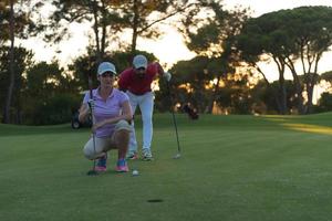 casal no campo de golfe ao pôr do sol foto