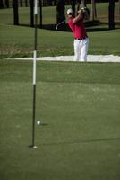 golfista acertando um bunker de areia foto