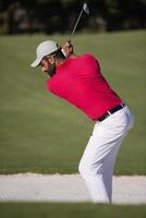 golfista acertando um bunker de areia foto