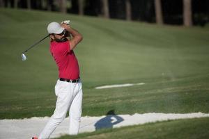 golfista acertando um bunker de areia foto