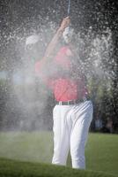 golfista acertando um bunker de areia foto