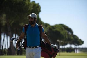 jogador de golfe andando e carregando bolsa foto