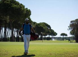 jogador de golfe andando e carregando bolsa foto