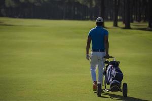 jogador de golfe andando com bolsa de rodas foto