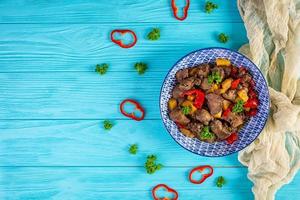 delicioso fígado de frango frito com pimenta, maçãs e ervas na luz de fundo de madeira. vista do topo foto