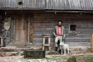 hipster com cachorro na frente da casa de madeira foto