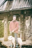 jovem hippie com cachorro na frente da casa de madeira foto
