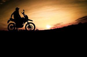 silhuetas masculinas e motos de motocross de turismo. parque para relaxar nas montanhas à noite. conceito de viagens e lazer de aventura foto