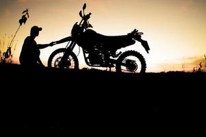 silhuetas masculinas e motos de motocross de turismo. parque para relaxar nas montanhas à noite. conceito de viagens e lazer de aventura foto