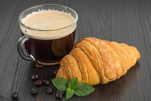 café com croissant em fundo de madeira foto