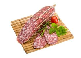 salame na placa de madeira e fundo branco foto