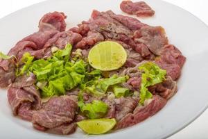 carpaccio de carne na chapa e fundo branco foto