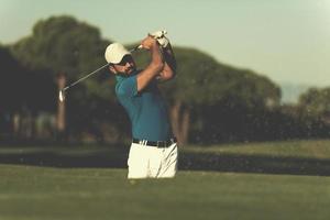 golfista profissional acertando um tiro de bunker de areia foto