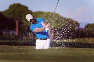 golfista profissional acertando um tiro de bunker de areia foto