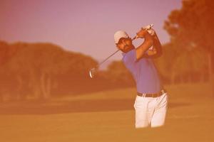 golfista profissional acertando um tiro de bunker de areia foto