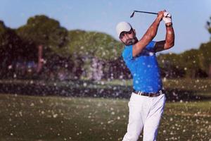 golfista profissional acertando um tiro de bunker de areia foto