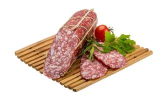 salame na placa de madeira e fundo branco foto