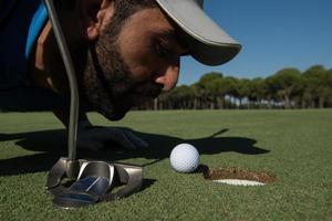 jogador de golfe soprando bola no buraco foto