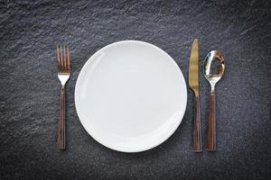 colocar comida de mesa com conjunto de prato branco em toalhas de mesa ou guardanapo no jantar prato vazio colher garfo e faca na mesa foto