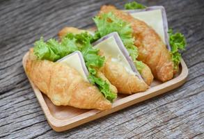 croissant salada presunto vegetal - sanduíches de croissant na mesa de madeira foto