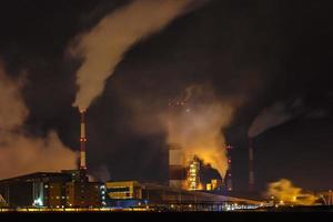 noite paisagem industrial poluição ambiental resíduos de usina termelétrica. grandes tubos da planta da empresa da indústria química foto