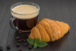 café com croissant em fundo de madeira foto