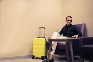 homem com mala relaxante em um lobby. foto