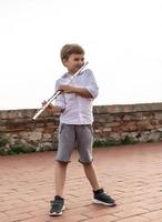 menino bonito tocando flauta ao ar livre. foto