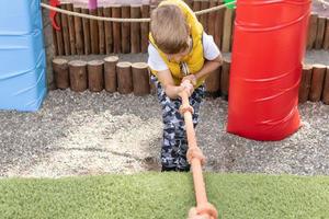 garoto puxando corda enquanto escalava no playground. foto