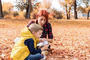 mãe e filho usando telefone celular no parque outono. foto