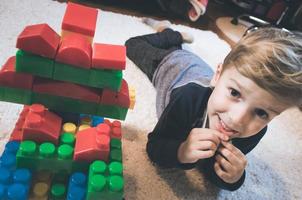 menino feliz e sua construção de blocos de brinquedo. foto