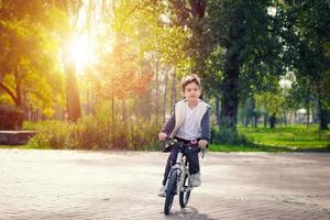 menino bonito andando de bicicleta no parque. foto